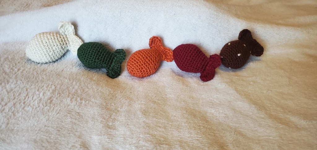 a picture of 5 crochet fish cat toys in different colors