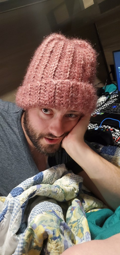 a picture of a man wearing a crochet hat in the color pink